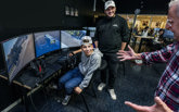 Två entusiastiska elever och lärare i ett klassrum med en körsimulator.