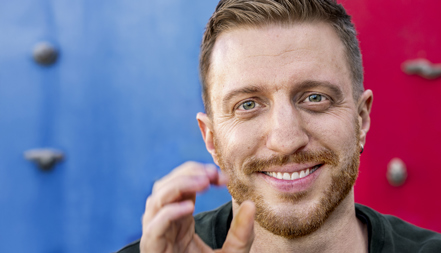 Glad, ung man framför färgglad bakgrund.