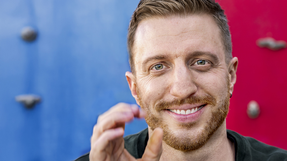 Glad, ung man framför färgglad bakgrund.