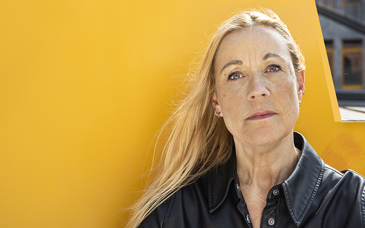 Kvinna med bestämd min som står framför gult föremål utomhus.