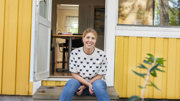 Sara Lundin sitter på en trapp framför ett gult hus.