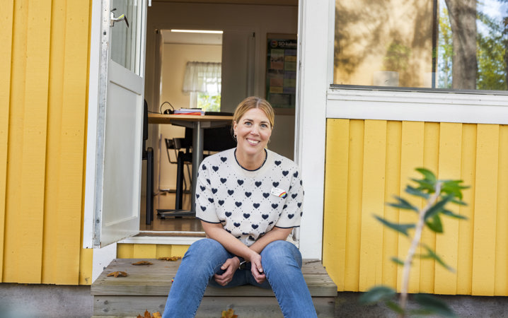 Sara Lundin sitter på en trapp framför ett gult hus.
