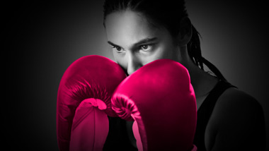 Kvinnlig boxare med händerna i boxhandskar framför ansiktet.