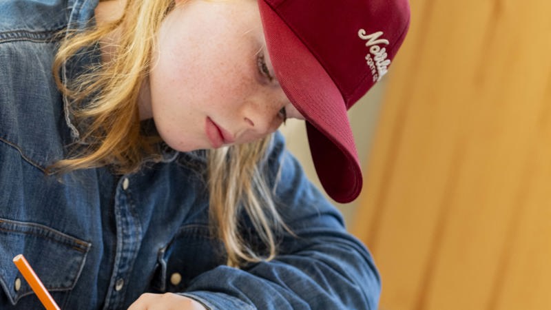 En elev sitter och skriver i sin loggbok.