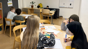 Sex elever sitter utspridda i ett klassrum.