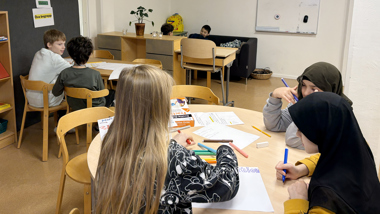 Sex elever sitter utspridda i ett klassrum.