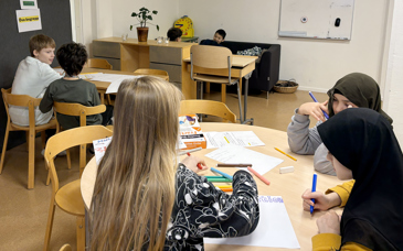 Sex elever sitter utspridda i ett klassrum.