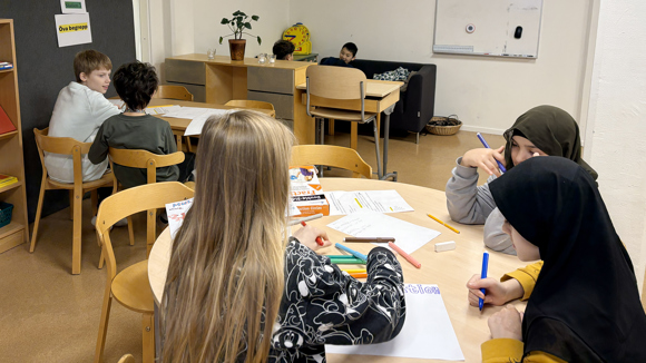 Sex elever sitter utspridda i ett klassrum.