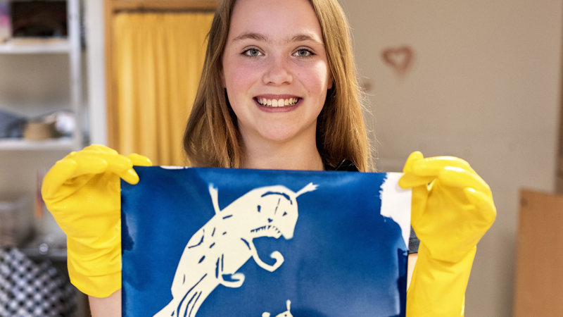 Glad elev visar upp konstverk.