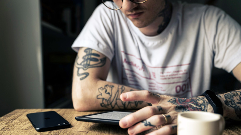 En person sitter med en läsplatta framför sig på bordet.