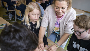Läraren Anna Jeppsson visar sina elever hur man kan göra med ett batteri.