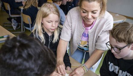 Läraren Anna Jeppsson visar sina elever hur man kan göra med ett batteri.