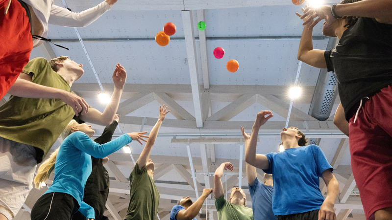 Personer står i ring och kastar upp bollar i luften.