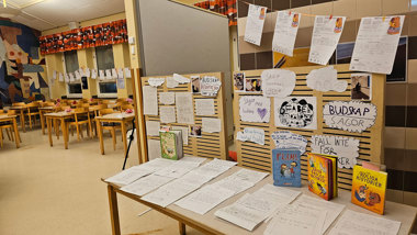 Matsal i skola dekorerad med böcker och teckningar.