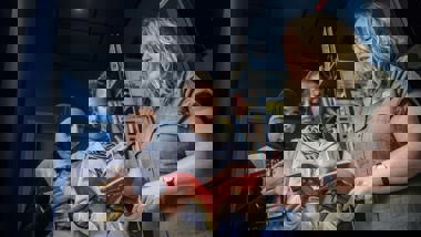 Kvinna som pekar i en bok och pratar med två flickor