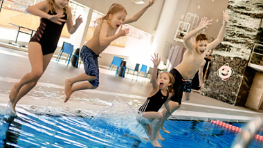 Barn hoppar från bassängkant.