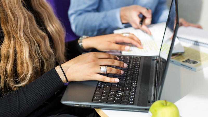 Kvinnohänder som skriver på en laptop