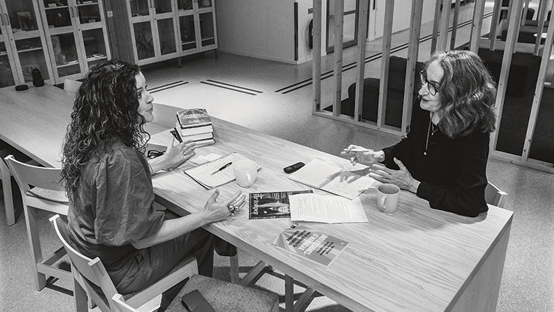 Intervjusituation med två kvinnor som samtalar vid ett bord. Svartvit bild.