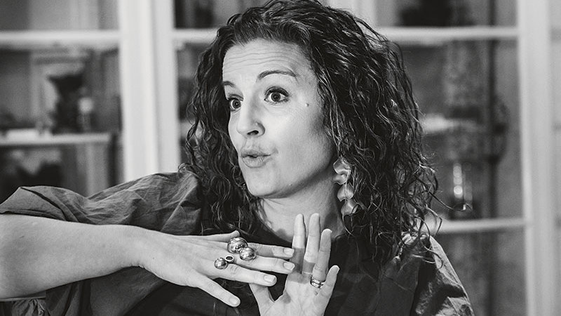 Kvinna som gestikulerar och grimaserar när hon förklarar något. Svartvit bild. 