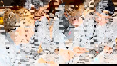 Lärare diskuterar med elever under lektion.