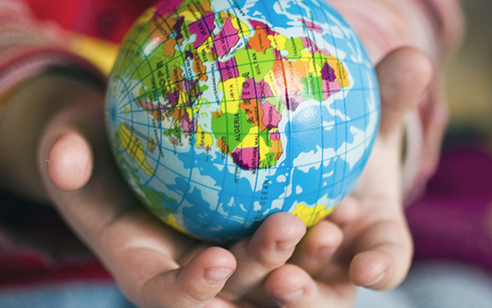 Två barnhänder håller i en liten jordglob.