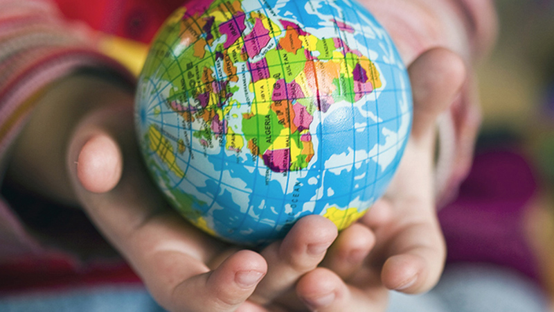 Två barnhänder håller i en liten jordglob.