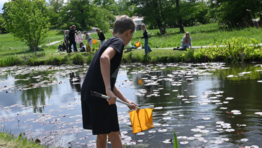Elev med håv står framför ett vattendrag.