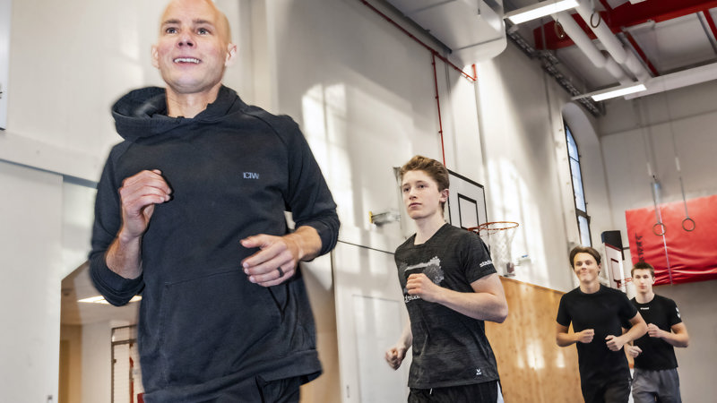 Patrik Mårdh springer med elever i gympasalen.