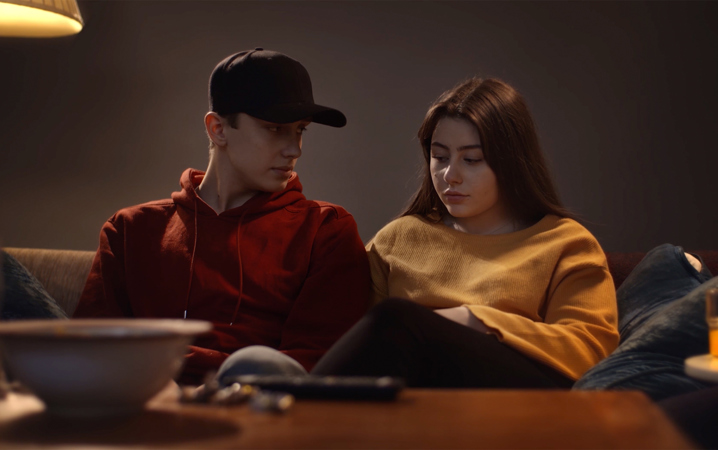 Två ungdomar sitter bredvid varandra i en soffa.