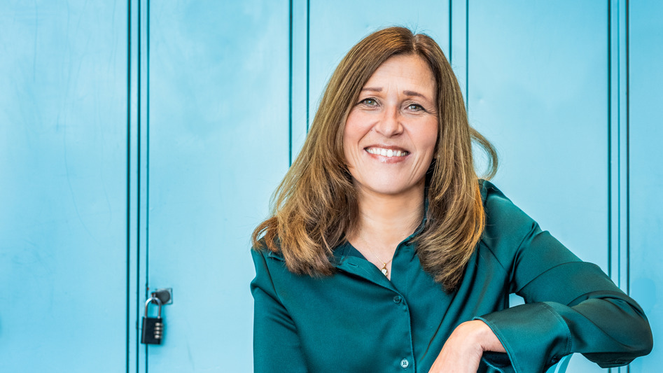 Person som sitter och ler på en stol i en skolkorridor.