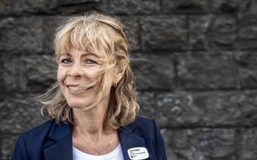 Levande porträttfoto av leende kvinna med blåst i håret.