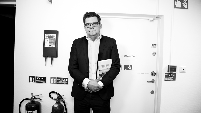 Svartvit bild på allvarlig man som står vid en nödutgång, foto.